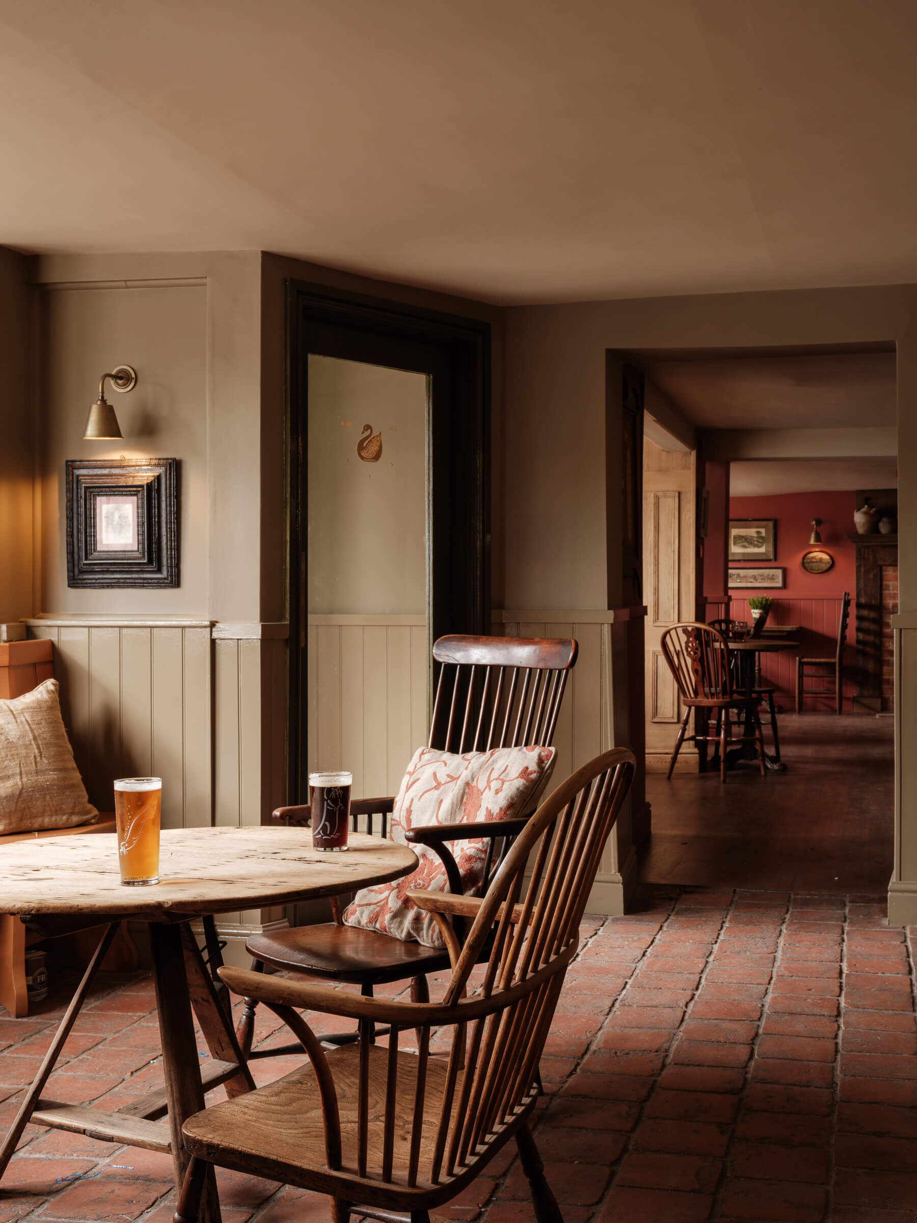 Pub interior, with paintings, beer pints on a table, and wooden chairs